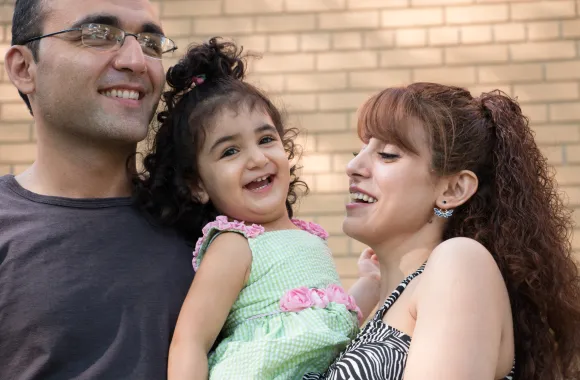 Couple holds child laughing.